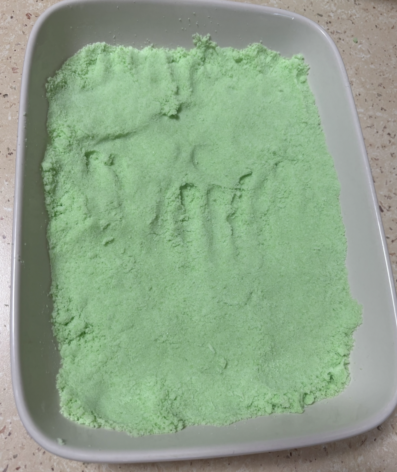 A tub of allergen-free handmade green kinetic sand