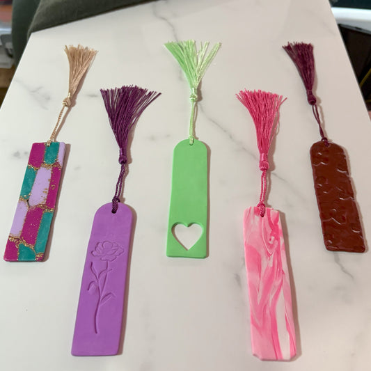 Set of five colorful bookmarks with tassels on a marble surface