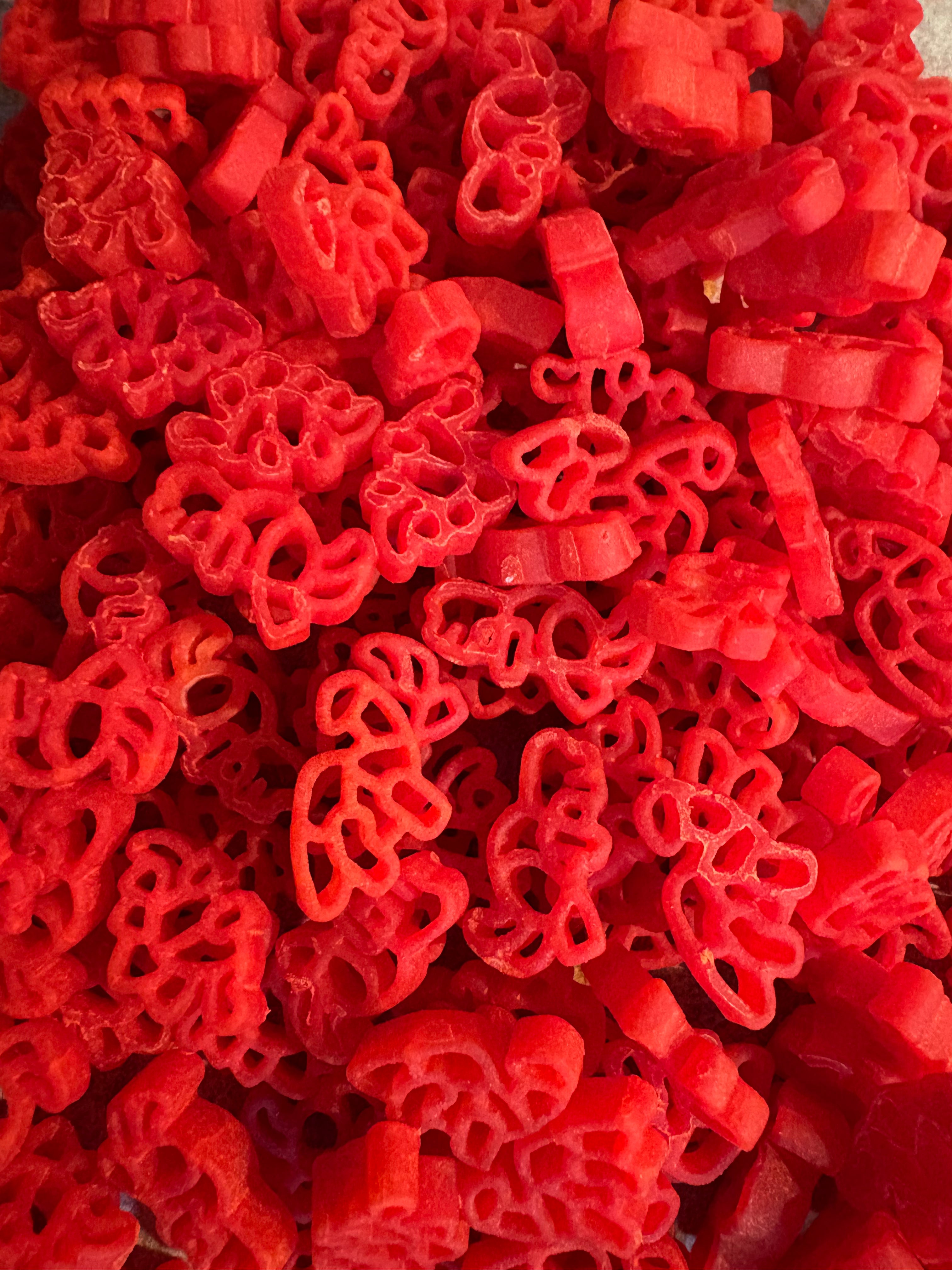 Some of Krafty Kat's Sensory Pasta being coloured red dinosaurs